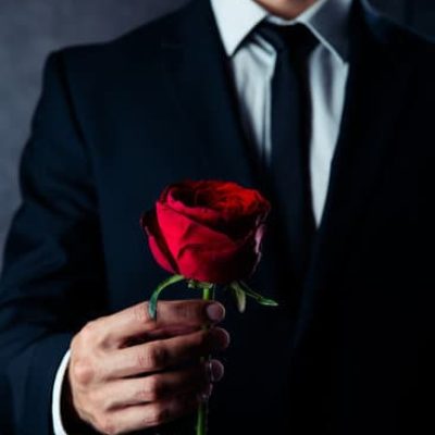 canva cropped photo of business man holding a red rose in his hand. he is wearing formal wear MADauaUHBFs
